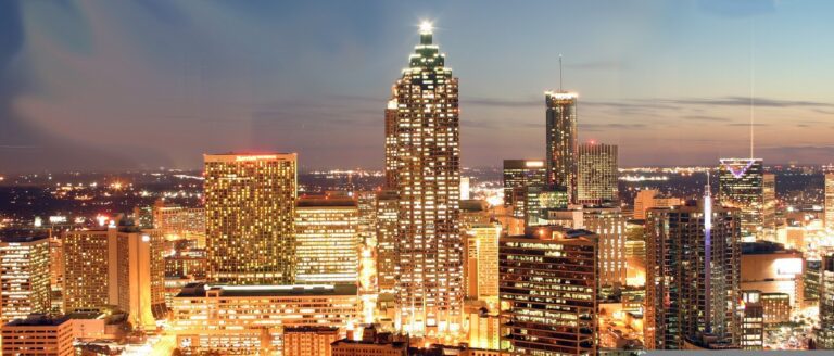 City skyline at dusk with illuminated buildings.
