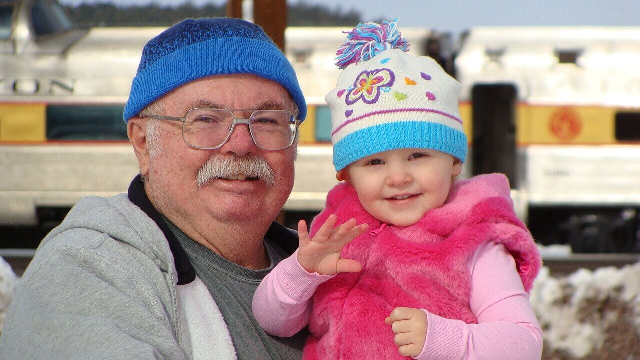 Grandfather and child smiling in winter clothing.