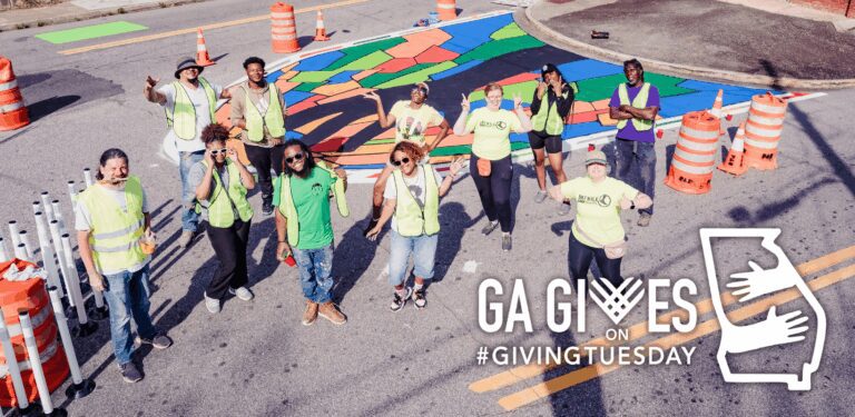 Group of volunteers painting colorful street mural.
