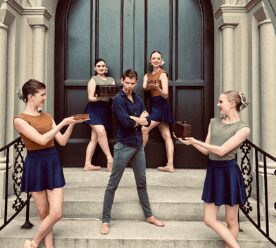 Five dancers posing on building steps.