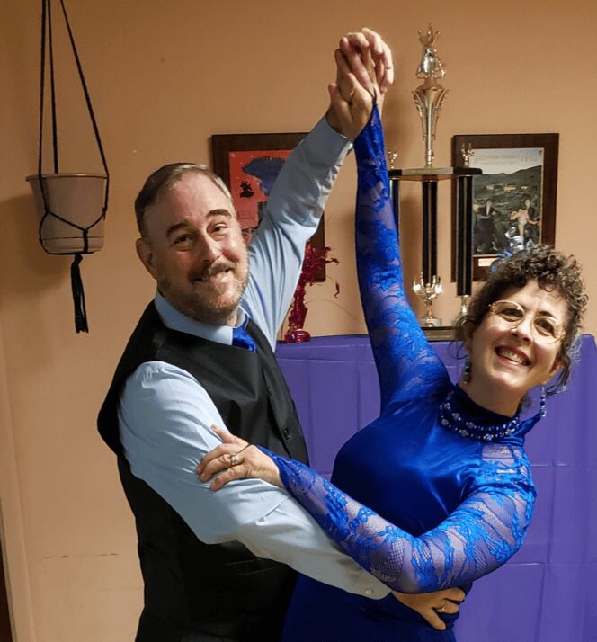 Couple dancing in formal attire, smiling happily.