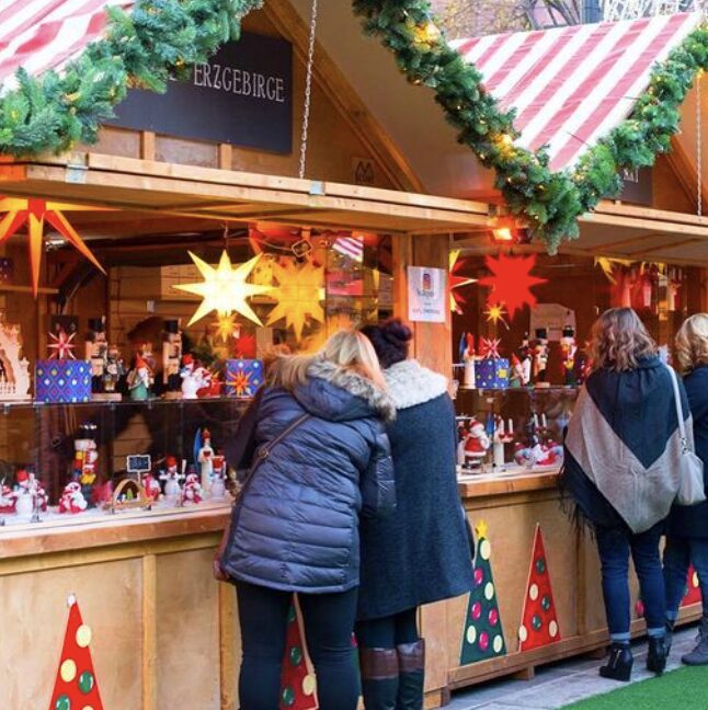 People shopping at festive Christmas market stalls.
