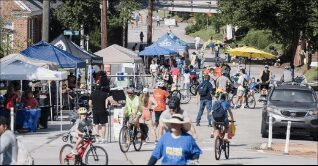 Street festival with cyclists and vendor tents.