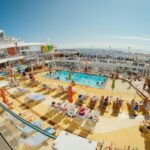 A vibrant scene of people relaxing by a pool on a luxurious cruise ship deck.