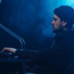 A man working on a computer in a dimly lit room, focusing on cybersecurity.