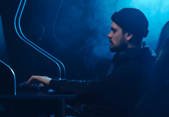 A man working on a computer in a dimly lit room, focusing on cybersecurity.