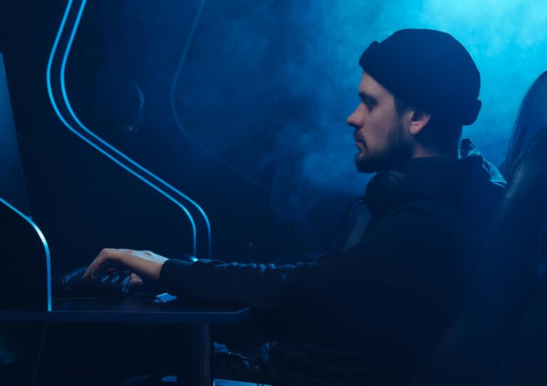 A man working on a computer in a dimly lit room, focusing on cybersecurity.