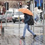 A man walks with an orange umbrella on a rainy day in Istanbul, Türkiye.