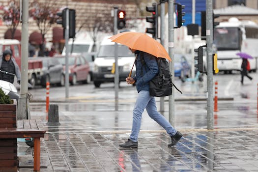 A man walks with an orange umbrella on a rainy day in Istanbul, Türkiye.