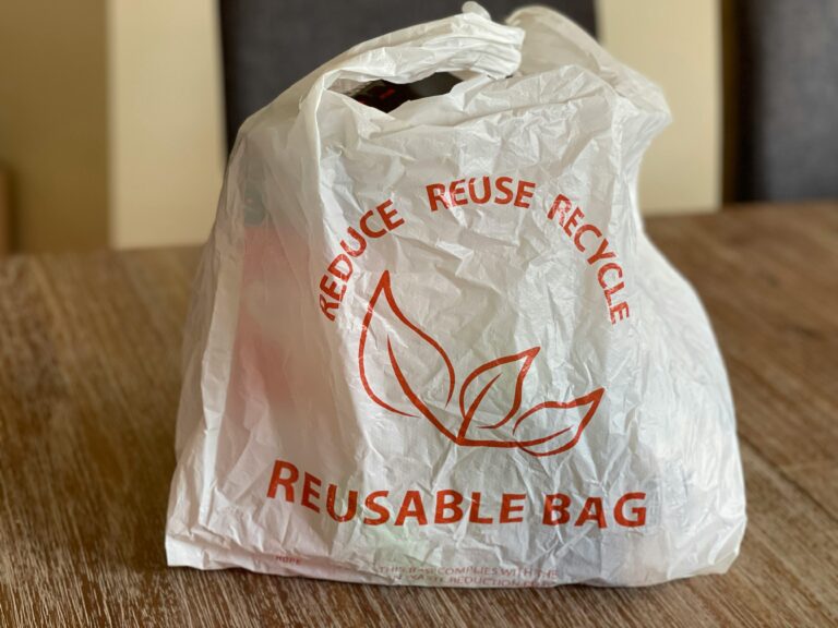 Reusable bag promoting reduce, reuse, recycle on a wooden table indoors.
