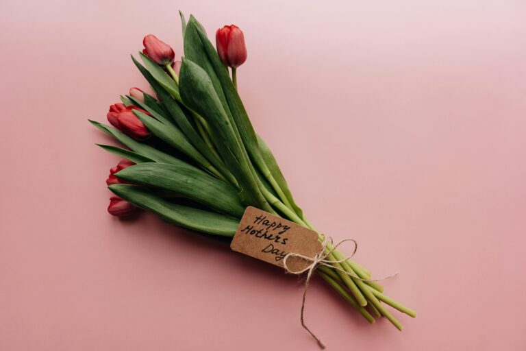 Elegant bouquet of red tulips with 'Happy Mother's Day' tag on pink background, perfect for celebrating Motherhood.