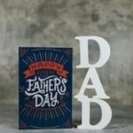 Close-up of a stylish Father's Day card with 'DAD' decorative letters on a textured background.